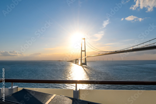 View of the setting sun over the Öresund Bridge which spans the strait between Sweden and Denmark from a boat on the Baltic Sea.