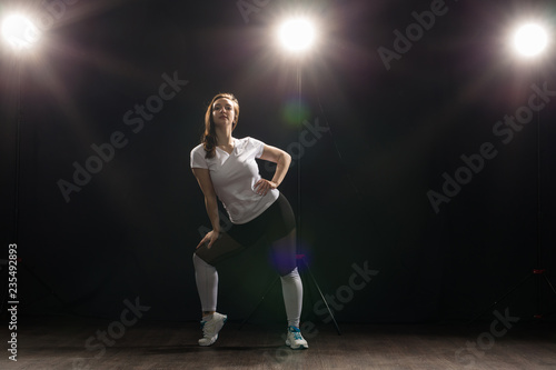 Young woman dancer gymnastics exercise pose on dark background