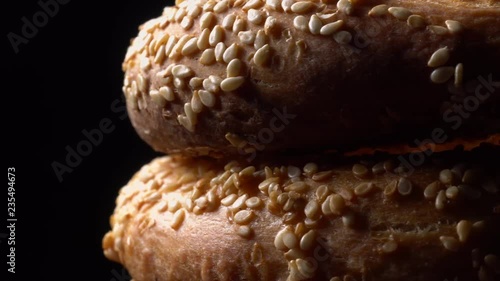 .Fresh bagels with sesame seeds in rotation. Black background. Extreme closeup.