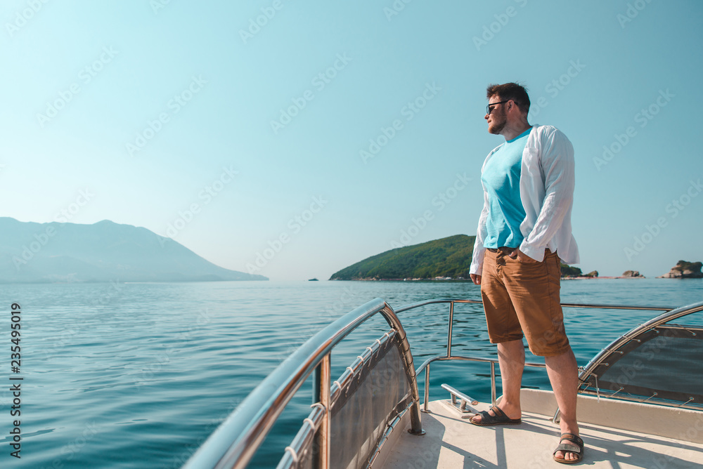 success man standing at nose of boat with sea and mountains on background success man standing at nose of boat with sea and mountains on background