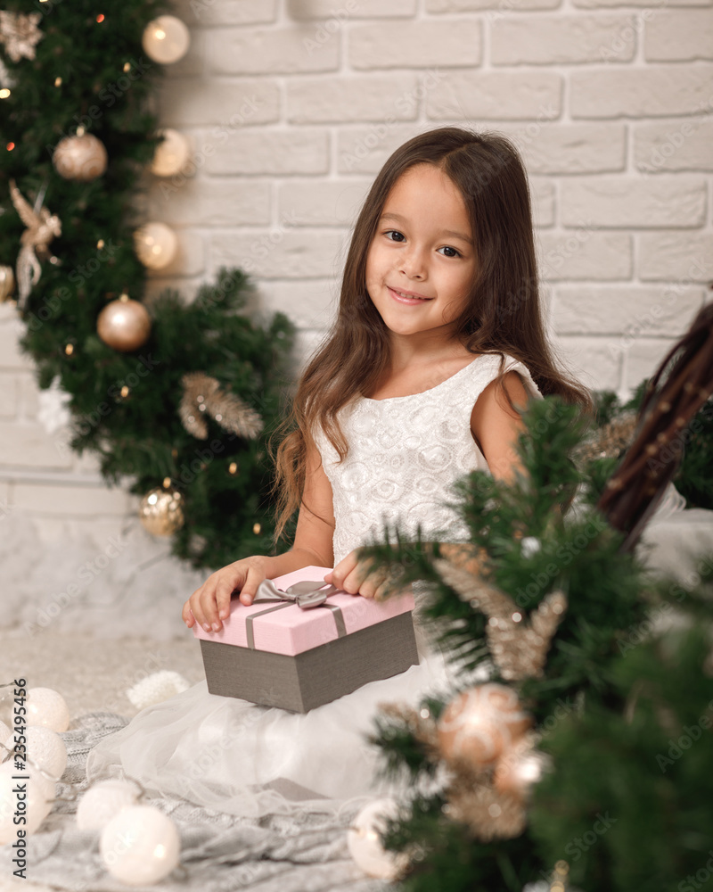 Pretty smiling girl holding Christmas gift in hand