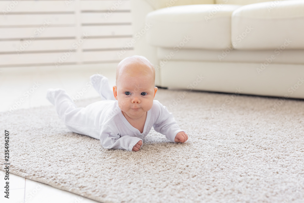 Childhood, infant and people concept - small baby lying on the floor Childhood, infant and people concept - small baby lying on the floor