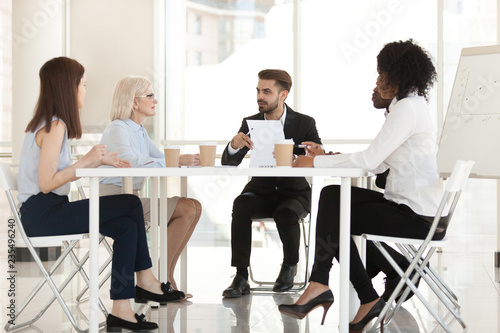 Diverse business people group discussing contract negotiating at modern office meeting, leader speaking to team presenting document report talking to multiracial board partners at executive briefing