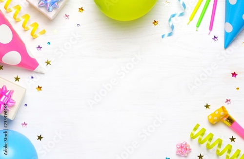 Birthday or party greeting card with copy space. Holiday frame or background with colorful balloon, gift, confetti, star, carnival cap and streamer. Top view.
