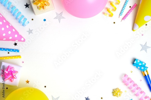 Holiday frame or background with colorful balloon, gift, confetti, silver star, carnival cap and streamer. Flat lay style. Birthday or party greeting card with copy space.