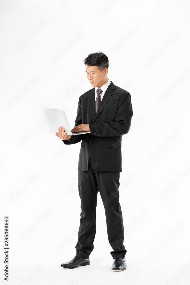 Business man in black suit standing and holding laptop