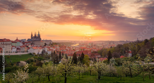A beautiful spring view of Prague at sunrise from Petrin hill. Prague Castle and St. Vitus Cathedral on the left and a golden rising sun in the background.