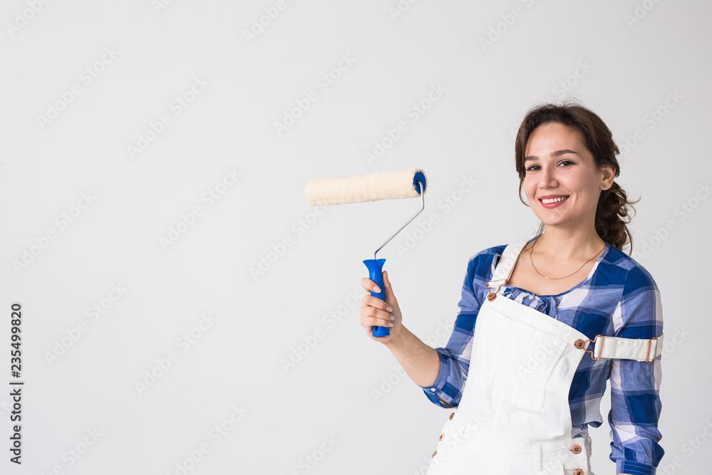 Repair, renovation, new home and people concept - young woman doing redecoration and show us thumbs up over white wall with copy space Repair, renovation, new home and people concept - young woman doing redecoration and show us thumbs up over white wall with copy space