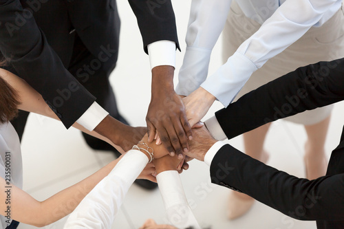 Diverse business people group put hands together in stack pile at training as concept of sales team corporate unity connection, teambuilding loyalty, support in teamwork, coaching, close up top view photo