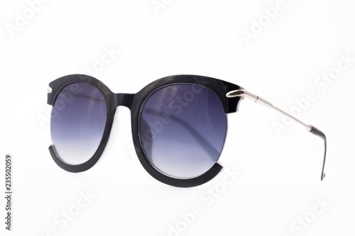 Women's sunglasses with purple tint stand frontally isolated on a white background with a shadow. Glasses rotated to the left.