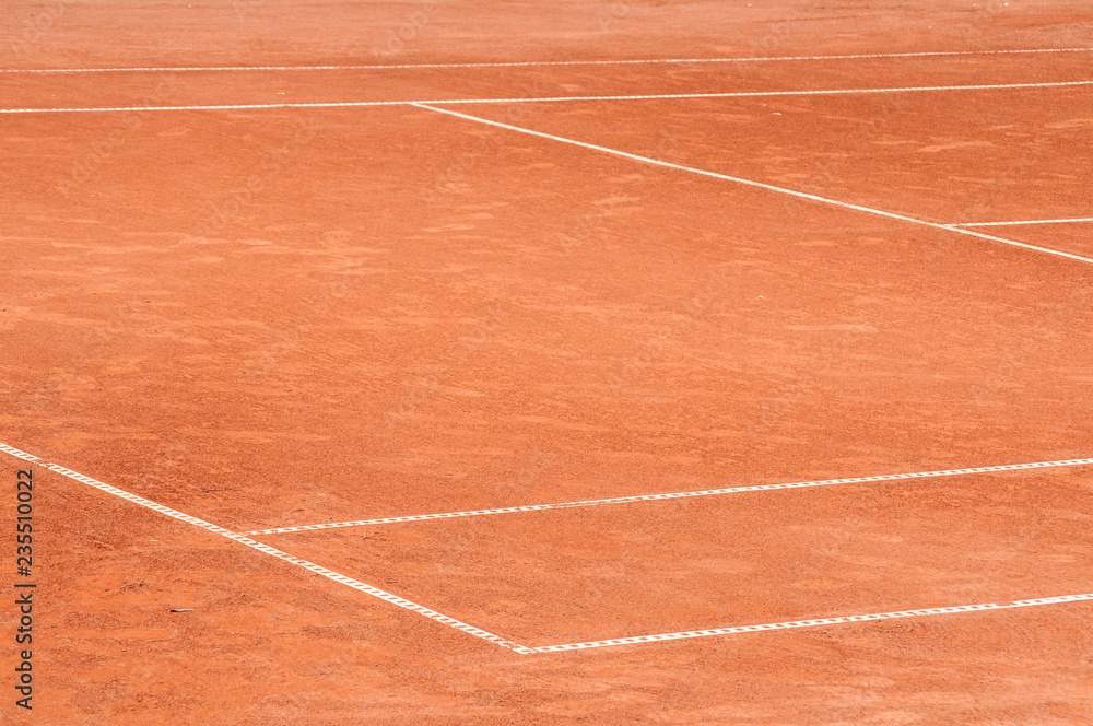 Part of empty used red clay tennis court playground surface with white lines closeup