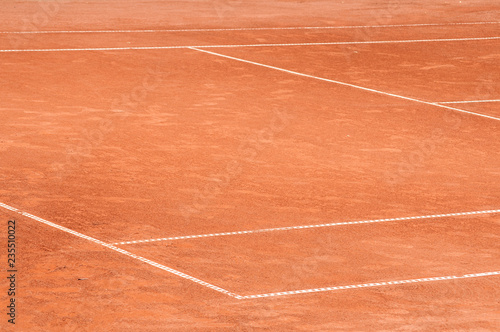 Part of empty used red clay tennis court playground surface with white lines closeup © varbenov