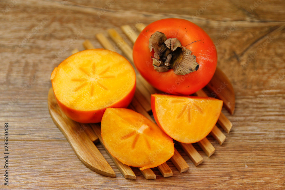 Ripe Persimmon kaki fruit or japanese apple. Close-up on wooden table, low light. Ripe Persimmon kaki fruit or japanese apple. Close-up on wooden table, low light.