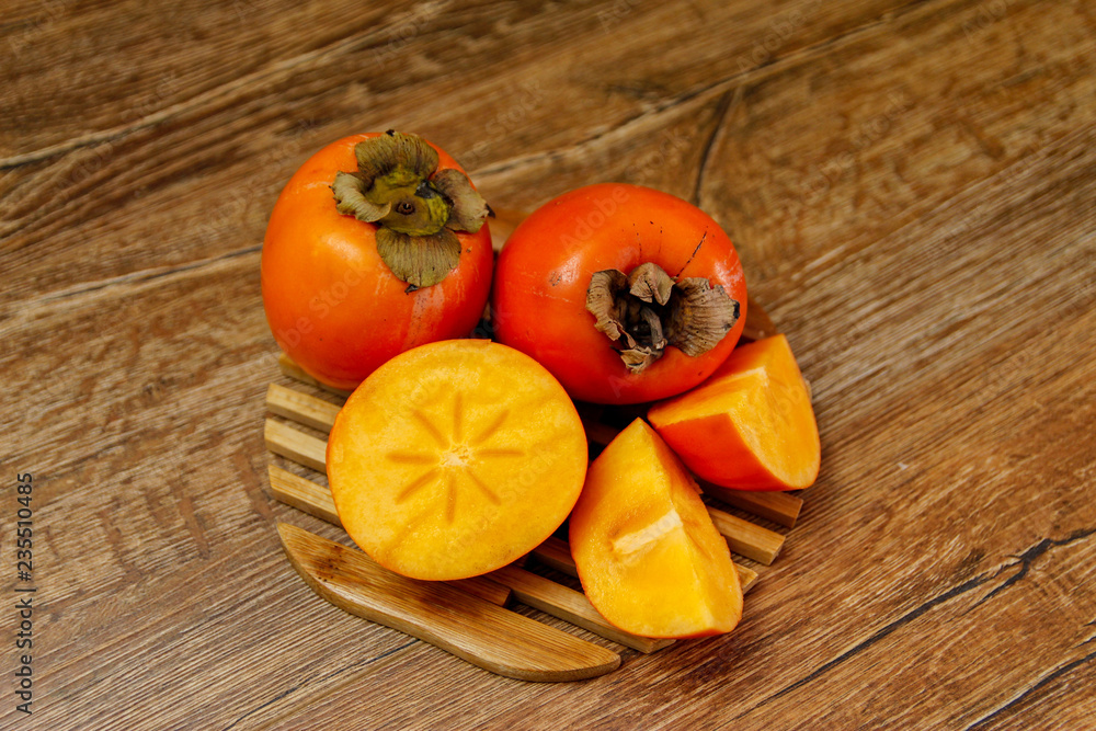 Ripe Persimmon kaki fruit or japanese apple. Close-up on wooden table, low light. Ripe Persimmon kaki fruit or japanese apple. Close-up on wooden table, low light.