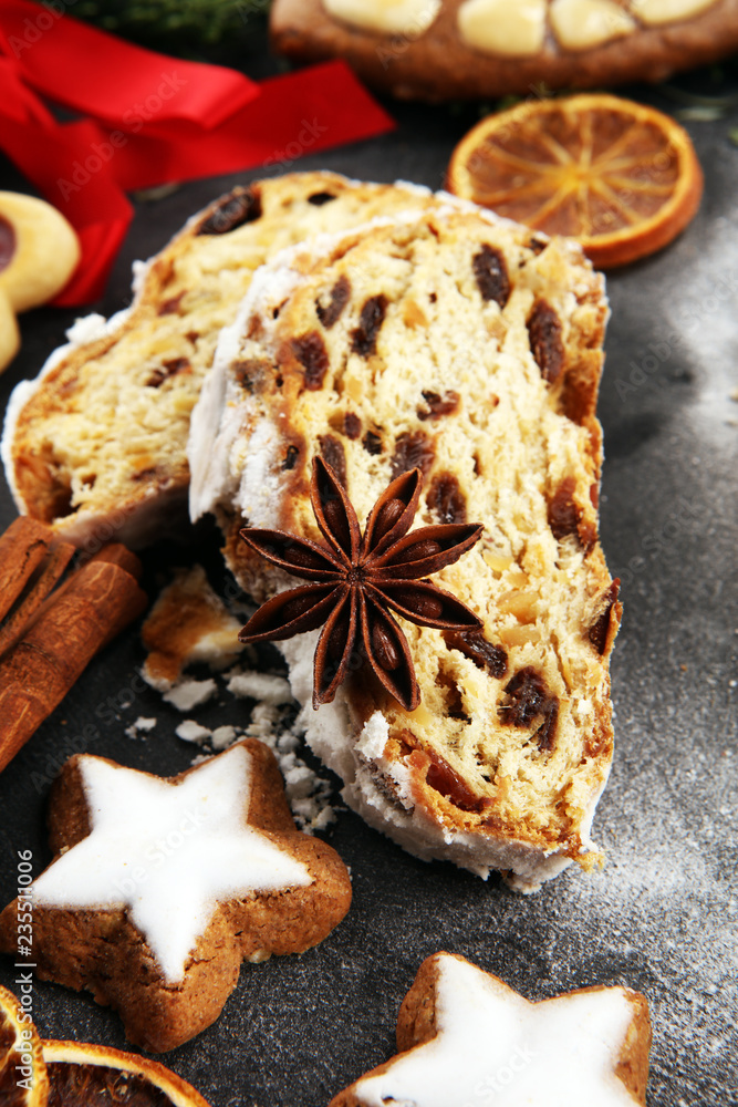 Traditional European Christmas pastry, fragrant home baked stollen, with spices and dried fruit. Sliced on rustic table with xmas tree branches and decorations