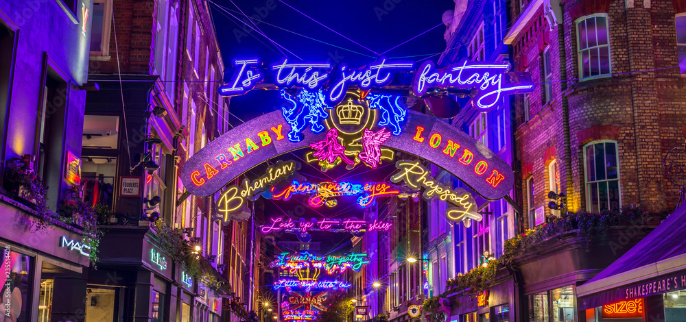 Lights down Carnaby Street in London during the Christmas Season. Large amounts of people can be seen. - obrazy, fototapety, plakaty 