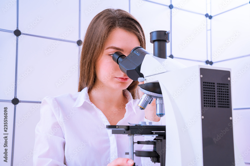 Young woman technician is examining a histological sample, a biopsy in the laboratory of cancer research Young woman technician is examining a histological sample, a biopsy in the laboratory of cancer research