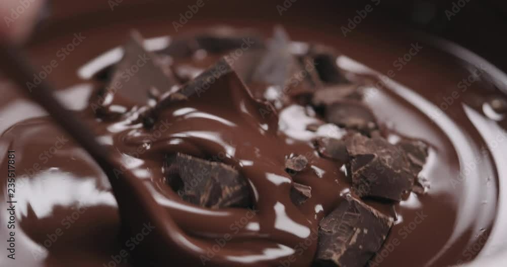 Slow motion closeup mixing chocolate chunks in melted dark chocolate Slow motion closeup mixing chocolate chunks in melted dark chocolate