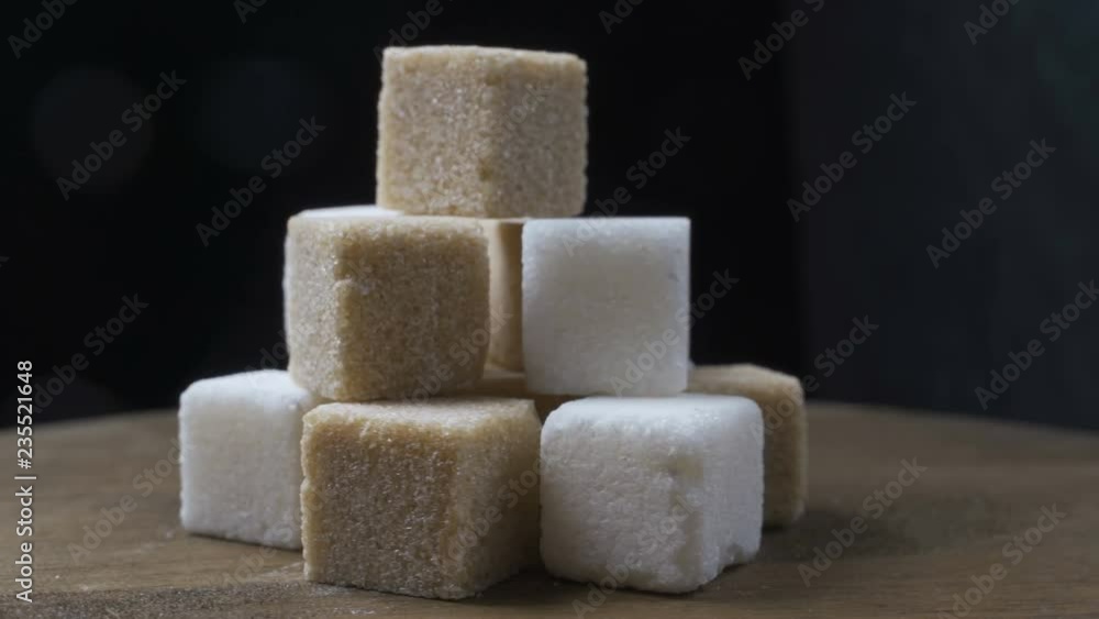 cubes of white and cane sugar rotate on a black background cubes of white and cane sugar rotate on a black background