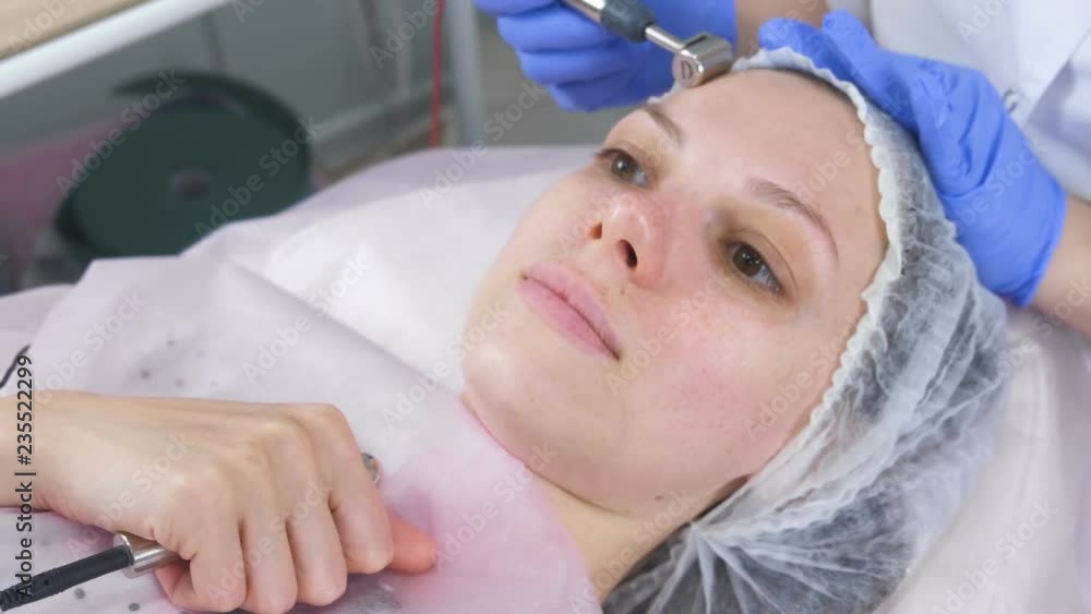 Cosmetologist makes a micro-current procedure for the face of a young woman. Face close-up. Cosmetologist makes a micro-current procedure for the face of a young woman. Face close-up.