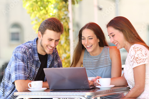 Three friends watching media content on laptop in a bar © Antonioguillem