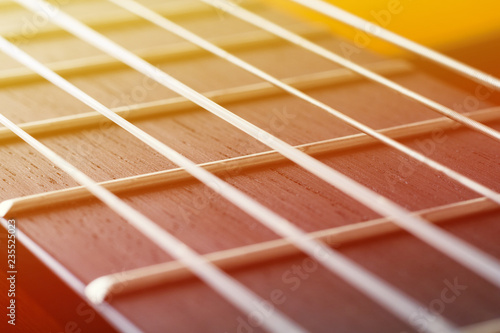 Canvas Print Close up view on a neck of acoustic guitar with strings illuminated by sunlight