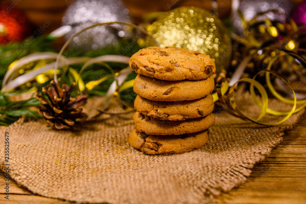 Stack of the chocolate chip cookies on sackcloth in front of christmas decorations