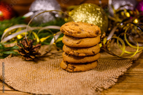 Stack of the chocolate chip cookies on sackcloth in front of christmas decorations
