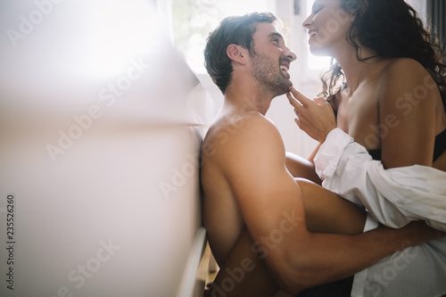 Young couple being intimate in bedroom. Sensual lovers making love in bedroom. photo