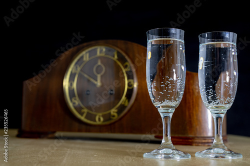An old clock and glasses full of champagne on New Year's Eve. Five minutes to the new year.