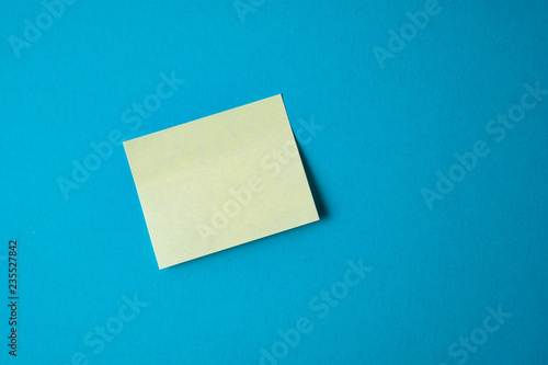 Yellow paper sticker on blue background. Close up.