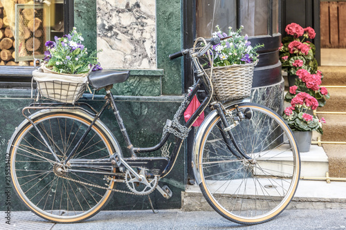 Vintage bicycle with a basket in front and behind, in front of a store