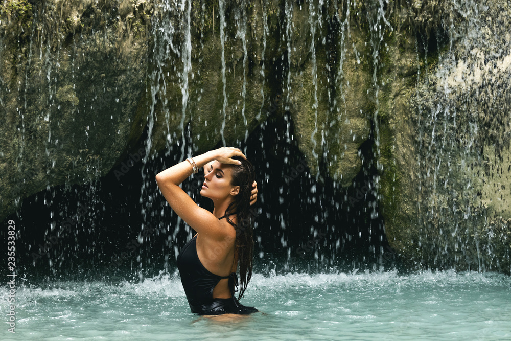 Naklejka premium Wet and sexy woman in beautiful waterfall with blue water