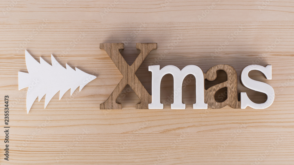 XMAS text with Christmas tree decor on wooden background XMAS text with Christmas tree decor on wooden background