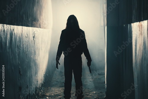 Silhouette of man maniac or killer or horror murderer with knife in hand in dark creepy and spooky corridor. Criminal robber or rapist concept in thriller atmosphere photo