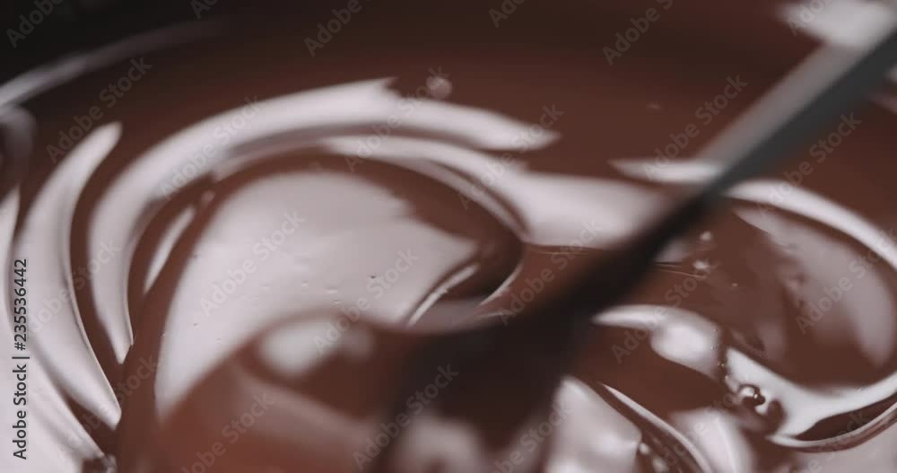 Slow motion closeup stirring melted dark chocolate with spoon Slow motion closeup stirring melted dark chocolate with spoon