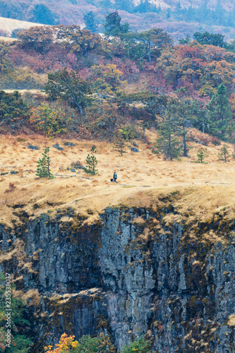 A woman walking a dog mountain cliff