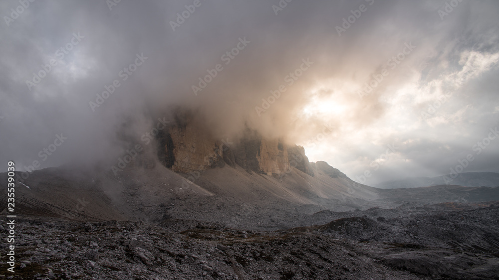 Tre Cime di Lavaredo mountain inside the clouds in sunset.