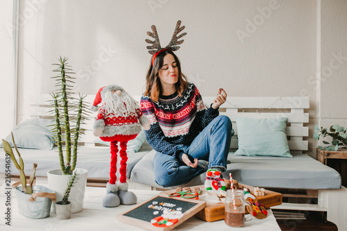 .Sweet and cheerful woman enjoying christmas at her home. Wearing christmas costume and eating tipical sweets. Lifestyle. Season photography.