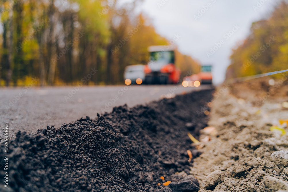 Laying a new asphalt on the road. Worker operating asphalt paver machine during road construction. Construction of the road. Laying a new asphalt on the road. Worker operating asphalt paver machine during road construction. Construction of the road.