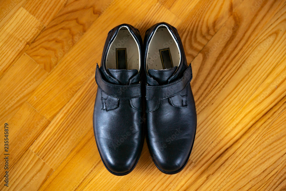 New classic leather shoes on a wooden background. Top view of boys shoes in the centre on wooden surface. New classic leather shoes on a wooden background. Top view of boys shoes in the centre on wooden surface.