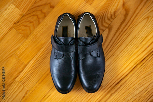 New classic leather shoes on a wooden background. Top view of boys shoes in the centre on wooden surface.