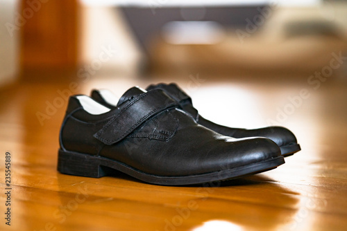 Black school shoes for a boy on a wooden surface. Contemporary design, daily wear men's black shoes over the wooden background.