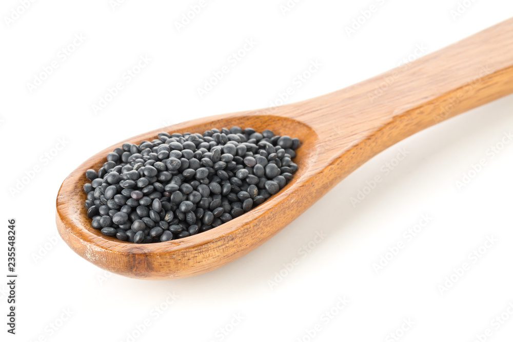 Heap of black organic beluga lentils in wooden spoon on white Heap of black organic beluga lentils in wooden spoon on white