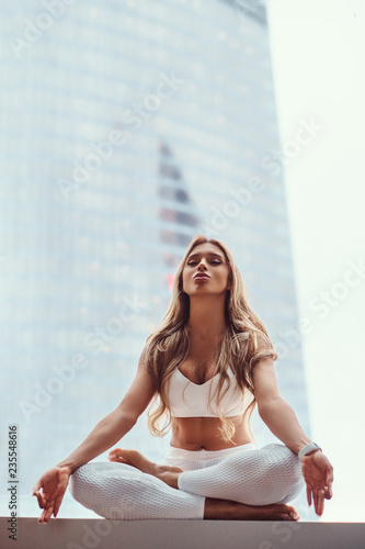Beautiful fitness model meditating in a living apartment.