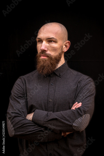 bald man with a beard in a black shirt on a dark background
