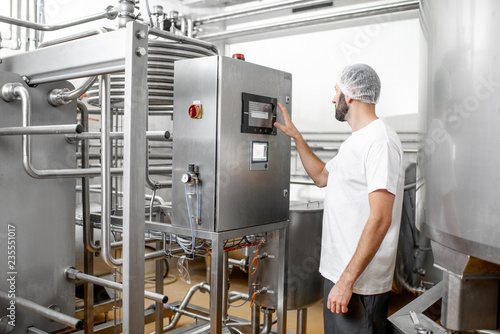 Εκτύπωση καμβά Worker operating pasteurizer using the control panel at the cheese or milk manuf