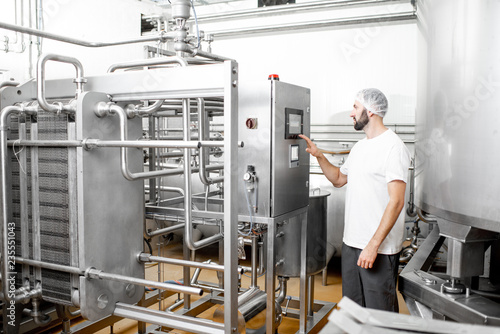 Worker operating pasteurizer using the control panel at the cheese or milk manufacturing photo