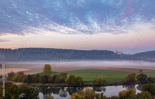 Morning view on castle Guttenberg, Haßmersheim, and river Neckar with fog in the fields from castle Horneck, Gundelsheim, Germany