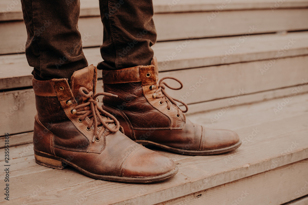 Image of mans brown footwear standing on wooden steps. Male in trousers and shaggy shoes on threshold. Horizontal view